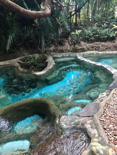 an outdoor pool with blue water surrounded by rocks and trees in the middle of it