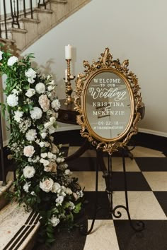 the welcome sign is next to a floral arrangement on a stand with a candle in it