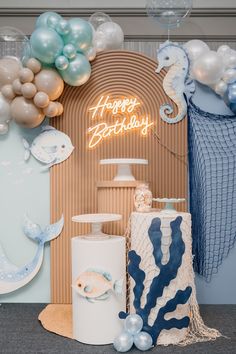 a birthday party with balloons and decorations on the wall, including an ocean themed cake