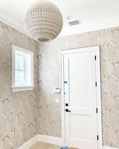 an empty room with a white door and wallpaper