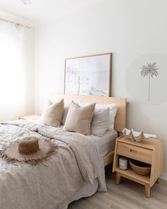 a bedroom with a bed, nightstand and hat on the end table in front of it