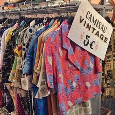 an assortment of clothing hanging on racks in a store with a sign that says camas vintage