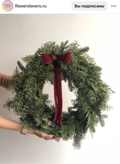 a person holding a wreath with red ribbon