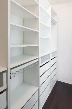 an empty closet with white shelves and drawers