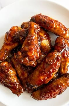 chicken wings covered in bbq sauce on a white plate