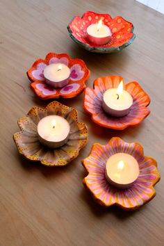 four candles are sitting in flower shaped bowls