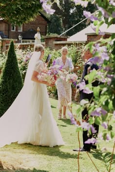 the bride and groom are walking through the garden with purple flowers in their hands,