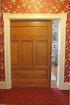 an open door in a room with red carpet and floral wallpaper on the walls