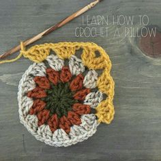 a crocheted dishcloth with an orange and white flower on it, next to a knitting needle