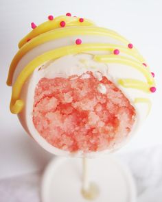 a cake pops covered in frosting and sprinkles on a white stand