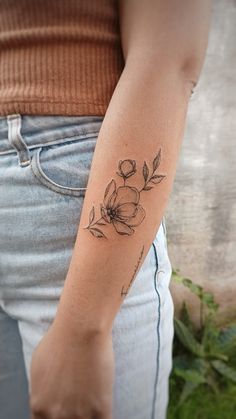 a woman's arm with a flower tattoo on the left side of her arm