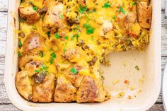 a casserole dish with chicken, cheese and vegetables in it on a wooden table