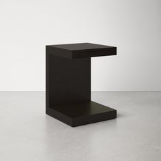 a black square table sitting on top of a white floor in front of a wall