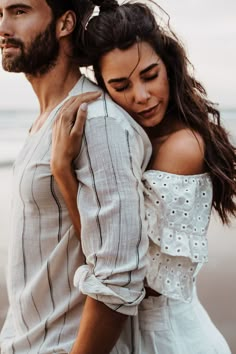 a man and woman embracing each other on the beach