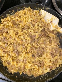 a skillet filled with pasta and meat on top of a stove