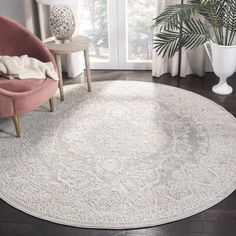 a large white rug in a living room with a pink chair and potted plant