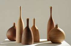 five wooden vases sitting on top of a white countertop next to each other