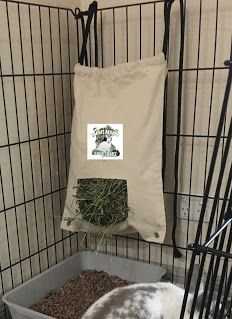 a caged in area with two rabbits and a bag of hay next to it