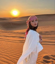 a woman standing in the desert at sunset