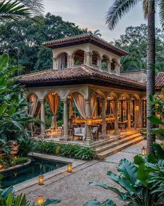 an outdoor gazebo surrounded by greenery and lit candles in front of a pool