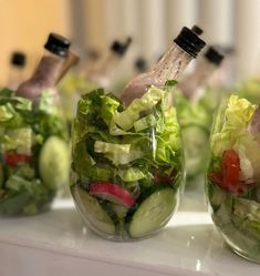 several glasses filled with different types of salads and dressing in them on a table