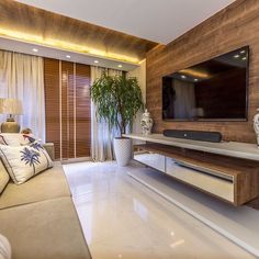 a living room with couches and a flat screen tv mounted to the side of a wall