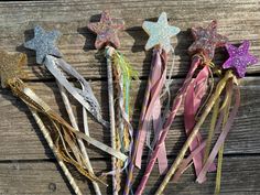 several different colored hair pins with stars on them sitting next to each other in front of a wooden fence