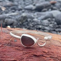 a close up of a bracelet on a piece of wood with rocks in the background