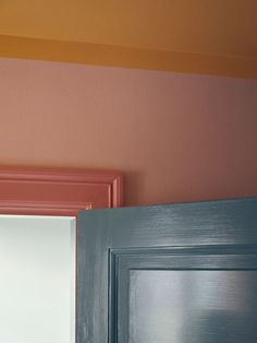 an open door in a room with pink and blue paint on the wall behind it