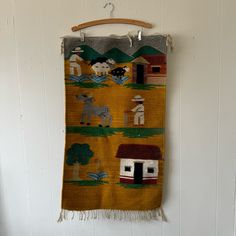 a wall hanging with animals and houses on it