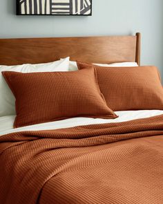 a bed with two pillows and an orange blanket