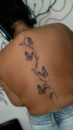 the back of a woman's shoulder with butterflies and leaves on her left side