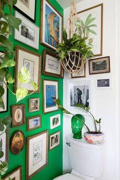 a bathroom with green walls and pictures hanging on the wall, including a potted plant