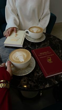 a woman sitting at a table with a book and cup of coffee in front of her