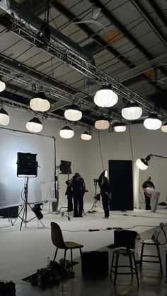 several people are standing in an empty room with lights on the ceiling and chairs around them