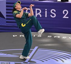 a woman in green pants and white sneakers is doing a trick on a trampoline