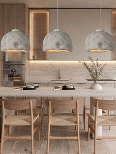 three pendant lights hanging from the ceiling above a kitchen island with chairs and countertop