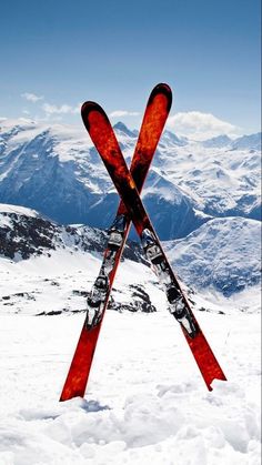 two skis sticking out of the snow with mountains in the background