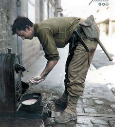 an old photo of a man washing his hands on the side of a fire hydrant