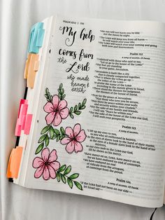 an open bible with pink flowers on it