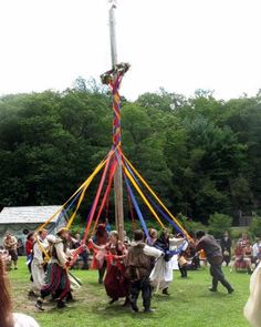 a group of people standing around a pole in the middle of a field with poles sticking out of it