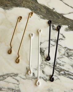 three different colored metal handles on a marble counter with black and white handles in the middle