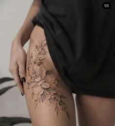 a woman's thigh with flowers on it and her hand touching the side of her leg