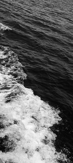 black and white photograph of the back end of a boat in the water with waves