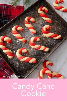 candy cane cookies on a baking sheet with red and white icing in the middle