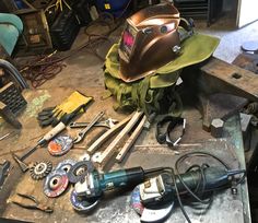 various tools are sitting on a workbench in a garage, including a welding helmet