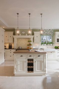 a large white kitchen with lots of counter space and lights hanging from the ceiling over the island