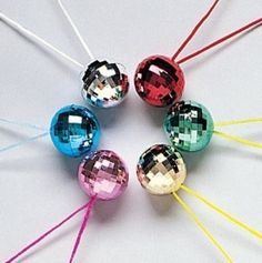 six different colored glass balls on a white surface with toothpicks in the middle