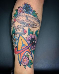 a tattoo on the leg of a person with flowers and an object in the background