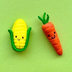 two plastic carrots and a corn on the cob with faces painted on them